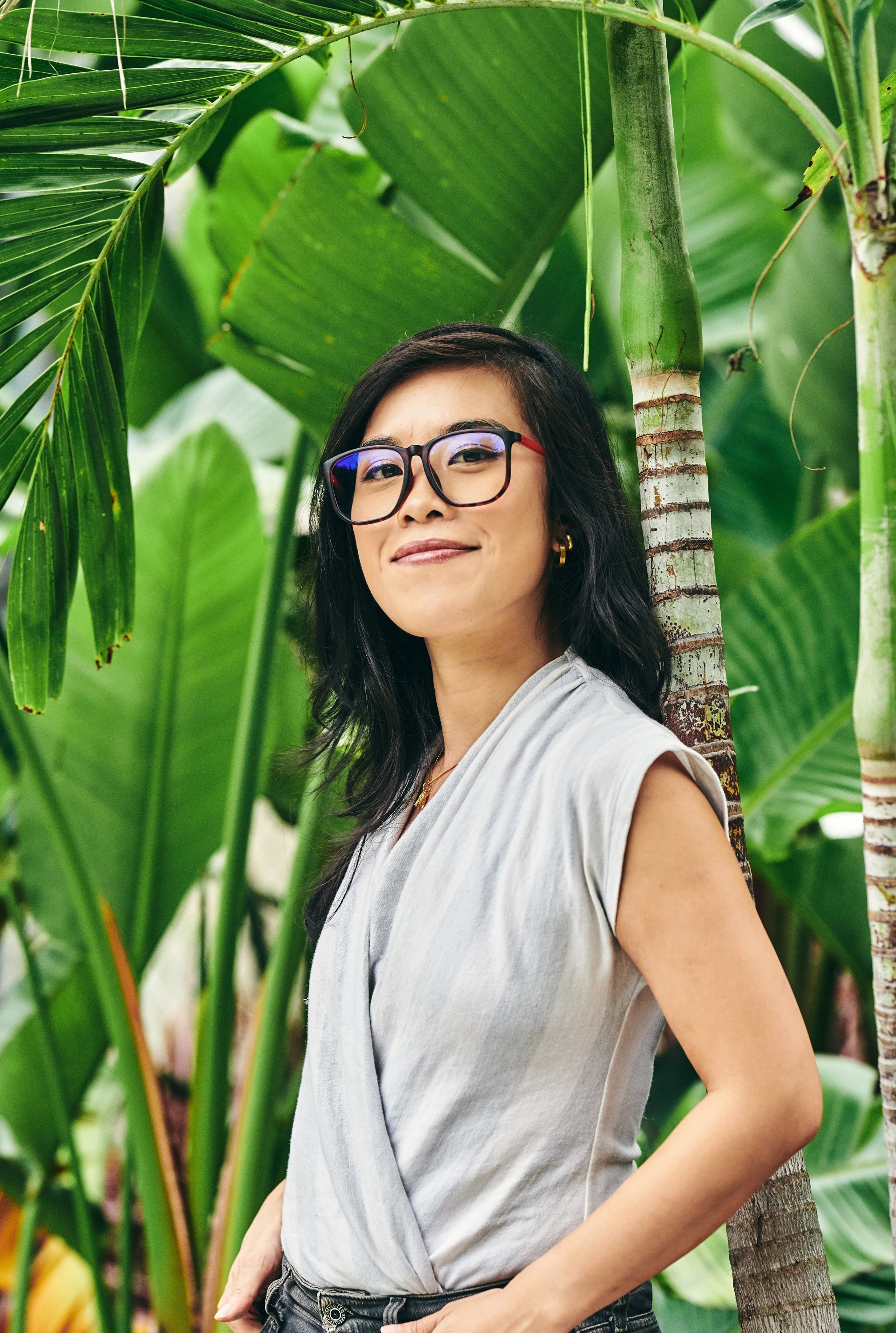 The author, wearing glasses and a white shirt, stands in front of a set of palm trees. Photo credit: Bryan Derballa